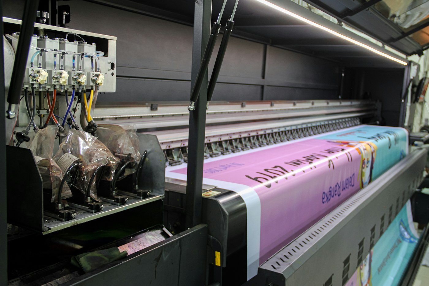 Imprimante grand format en train d'imprimer une bannière colorée dans un atelier d'impression